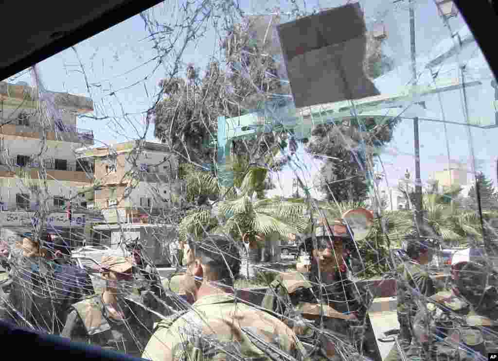 Syrian army soldiers are seen through a damaged military truck window which was attacked by a roadside bomb, in Daraa city, southern Syria, on May 9, 2012.