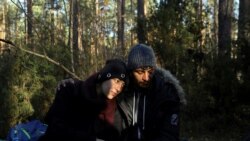 FILE - Syrian migrants Sara, 26, and Hassan, 24, sit on the ground in the forest after crossing the Belarusian-Polish border during the migrant crisis in Lewosze, Poland, Oct. 29, 2021.