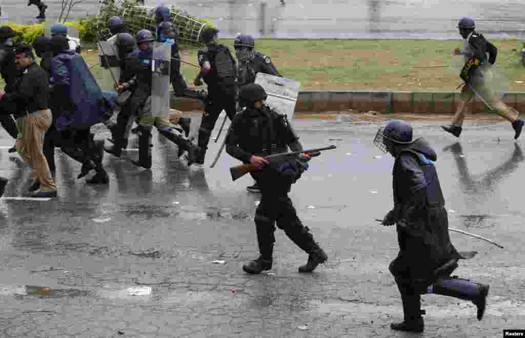 A police officer fires his weapon as he runs from demonstrators during the Revolution March towards the prime minister&#39;s house in Islamabad, Sept. 1, 2014.