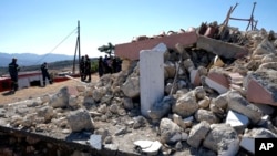 Firefighters stand next to a demolished Greek Orthodox church of Profitis Ilias after a strong earthquake in Arkalochori village on the southern island of Crete, Greece, Sept. 27, 2021. 