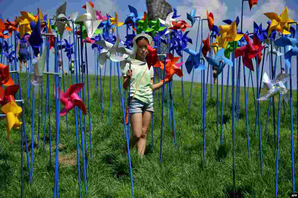 A girl spins pinwheels at a peace park, which was built to deliver the peace between North and South Korea, near the border village of Panmunjom in Paju, north of Seoul, South Korea.