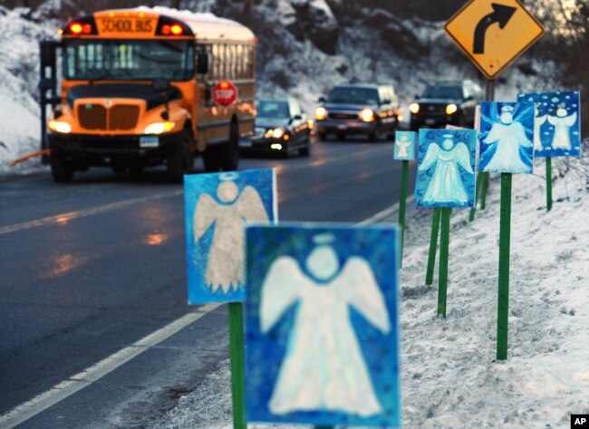 FILE - A bus traveling from Newtown, Conn., to Monroe stops in front of 26 angels along the roadside on the first day of classes for Sandy Hook Elementary School students since the Dec. 14 shooting, in Monroe, Conn., Jan. 3, 2013.