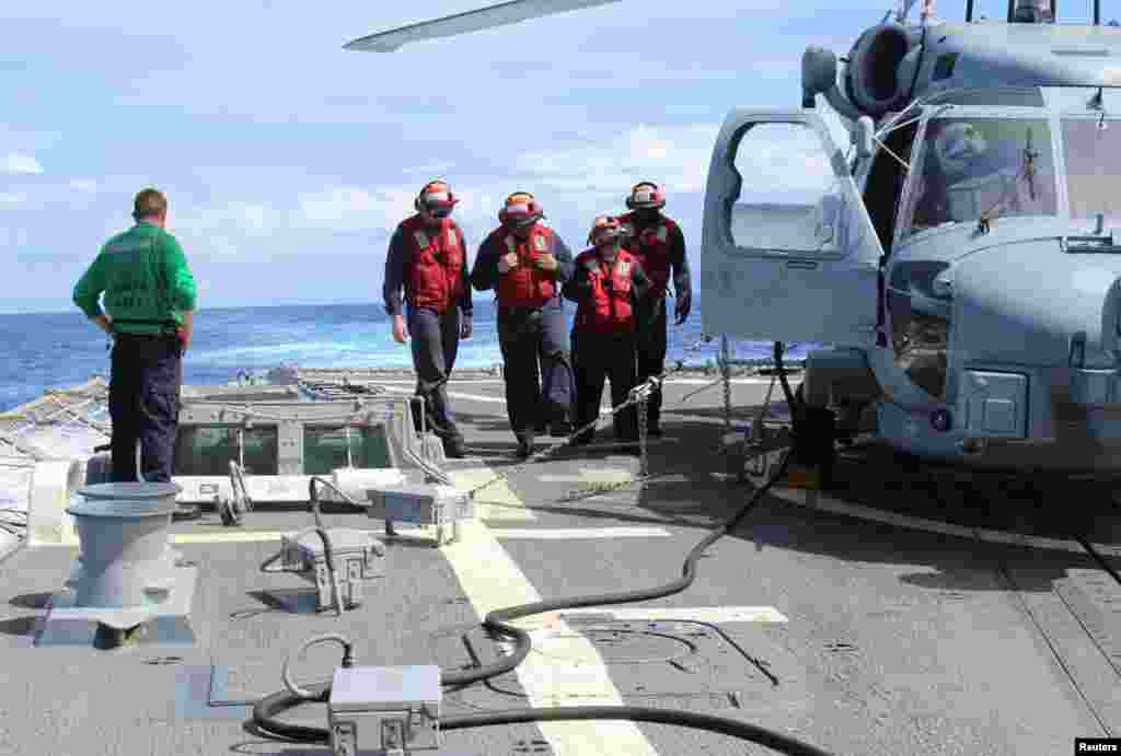 Sailors inspect the flight deck of the USS Kidd in this U.S. Navy handout picture, March 16, 2014. 