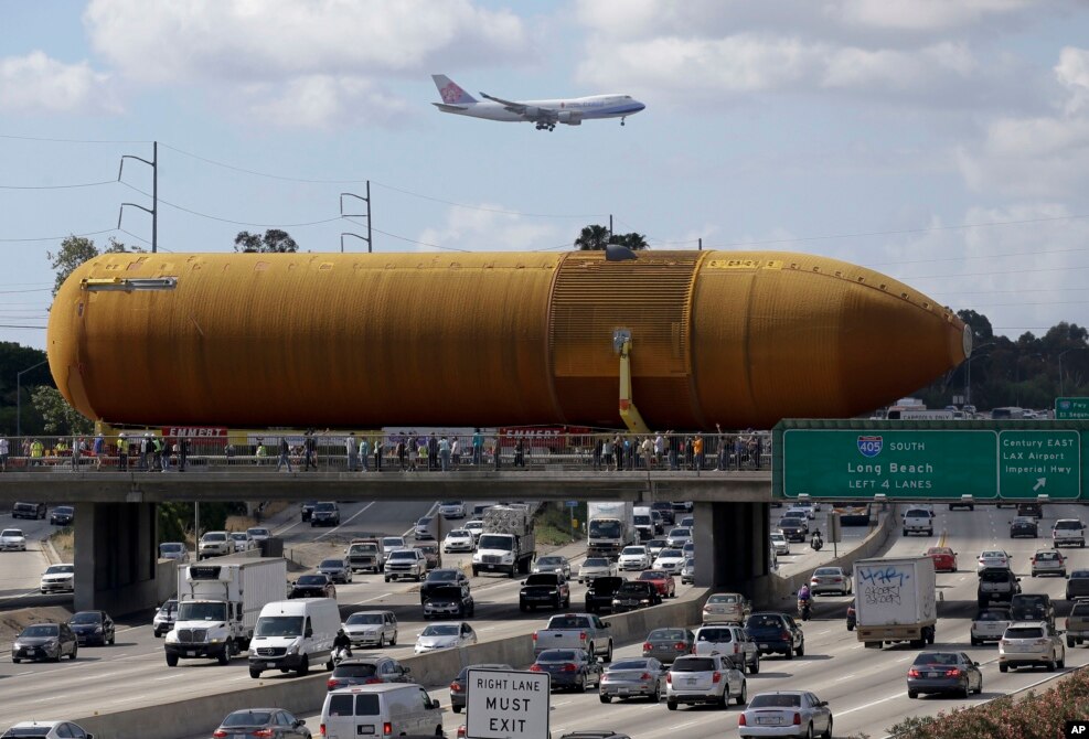 A cargo plane flies overhead as the last remaining space shuttle external propellant tank is moved across the 405 freeway in Los Angeles, California, USA, May 21, 2016.&nbsp;The ET-94 will be displayed with the retired space shuttle Endeavour at the California Science Center.