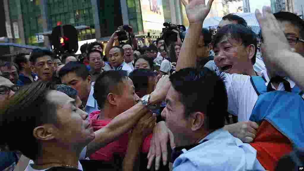 Des policiers tentent de contenir les résidents et les partisans pro-Pékin qui essayent d&#39;attaquer un étudiant, militant pro-démocratie, dans le quartier de Mong Kok, le 3 octobre 2014. 
