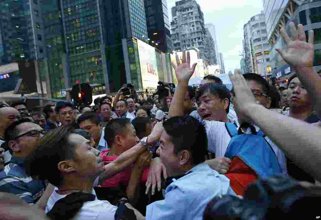 A local policeman scuffles with residents and pro-Beijing supporters as they try to attack a student pro-democracy activist in Mong Kok district, Oct. 3, 2014.