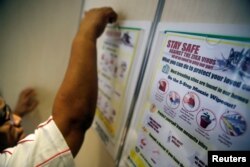 A resident volunteer puts up posters in a lift of a public housing estate in a Zika cluster in Singapore, Sept. 2, 2016.