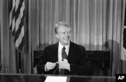 Presiden Jimmy Carter menyesuaikan mikrofon sebelum muncul di televisi dari Kantor Oval di Washington pada hari Jumat, 10 Desember 1978. (Foto: AP)