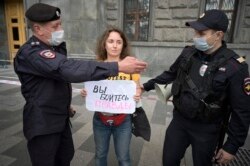 Polisi menahan seorang jurnalis yang memegang plakat bertuliskan "Anda takut akan kebenaran" dalam aksi solidaritas di Moskow, 21 Agustus 2021. (Natalia KOLESNIKOVA / AFP)