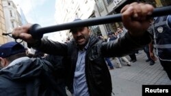 FILE - A plainclothes police officer reacts against journalists during a protest by anti-government demonstrators in central Istanbul, May 2014.