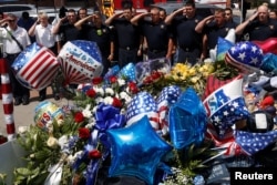 FILE - Members of the Dallas Fire Department salute after they brought a wreath of support to a makeshift memorial at police headquarters following the multiple police shootings in Dallas, Texas, July 11, 2016.