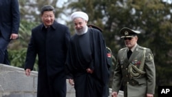 Presiden China Xi Jinping (kiri) disambut Presiden Iran Hassan Rouhani setibanya di Istana Saadabad di Teheran, Iran (23/1).