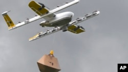 In this Tuesday, Aug, 7, 2018, photo a Wing Hummingbird drone carries a package of ice cream and popsicles as it leaves its launch site during a delivery flight demonstration in Blacksburg, Va. (Michael Shroyer via AP)