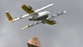 In this Tuesday, Aug, 7, 2018, photo a Wing Hummingbird drone carries a package of ice cream and popsicles as it leaves its launch site during a delivery flight demonstration in Blacksburg, Va. (Michael Shroyer via AP)