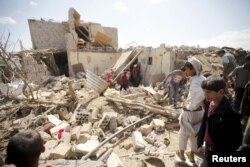 FILE - People inspect damage at a house after it was destroyed by a Saudi-led air strike in Yemen's capital Sana'a, Feb. 25, 2016.