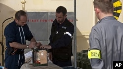 A BEA air accident inquiry official (R), seen in this image published on the web site of France's BEA air accident inquiry office surveys the handling of a flight data recorder aboard ship, May 2, 2011