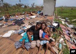 FILE - Sanjogeeta Kiran, right, with her sister Sulva Kiran, second left, and her children Shivendera, left, and Raajeen, sit amid the debris of their home in RakiRaki, Fiji, Feb. 24, 2016, after Cyclone Winston ripped through the island nation.