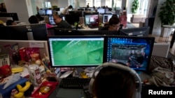 资料照：中国电子游戏开发公司的员工观看屏幕上显示的电游“光荣使命”。该款游戏由中国人民解放军南京军区和光荣使命网络联合推出（2013年8月2日）