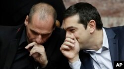 Greece's Prime Minister Alexis Tsipras chats with Greece's Finance Minister Yanis Varoufakis during a Presidential vote in Athens, on Wednesday, Feb. 18, 2015.