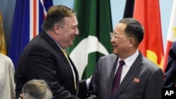 U.S. Secretary of State Mike Pompeo, left, greets North Korea's Foreign Minister Ri Yong-ho as they prepare for a group photo at the 25th ASEAN Regional Forum Retreat in Singapore, Saturday, Aug. 4, 2018.