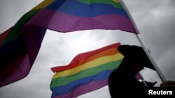 FILE -A woman holds rainbow flags for the grand entry at the International Gay Rodeo Association's Rodeo In the Rock in Little Rock, Arkansas, United States, April 26, 2015. 