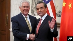 Chinese Foreign Minister Wang Yi gestures while shaking hands with U.S. Secretary of State Rex Tillerson before a bilateral meeting at the Diaoyutai State Guesthouse in Beijing, China, March 18, 2017. 