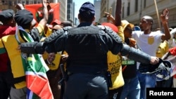 FILE - A police officer tries to control ANC supporters as they attempt to confront members of the opposition Democratic Alliance party marching in central Johannesburg, February 2014.