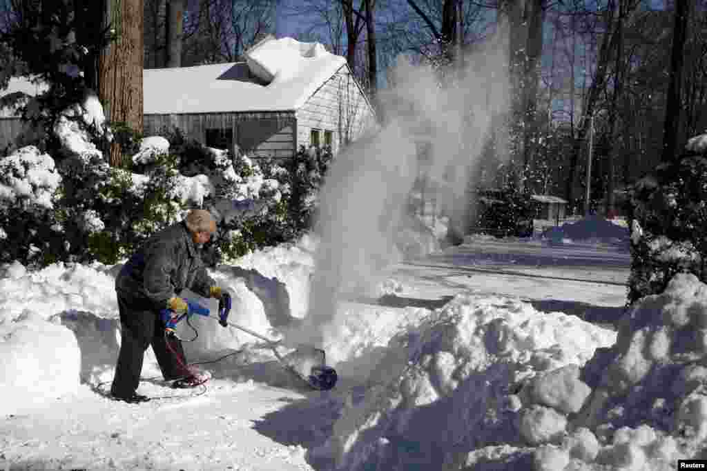 Frank Courtell clears snow from his driveway in the Washington suburb of Annandale, Va., Jan. 24, 2016. Most of Washington area is still recovering from the storm.