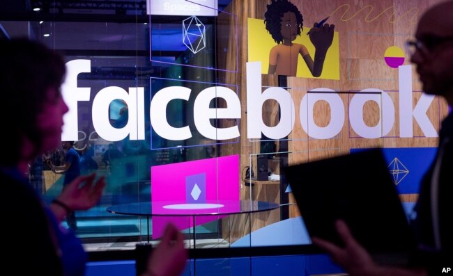 FILE - Conference workers speak in front of a demo booth at Facebook's annual F8 developer conference, in San Jose, California, April 18, 2017.