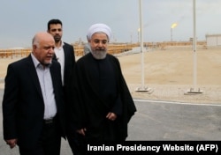 A handout picture released by the official website of the Iranian President Hassan Rouhani shows him (R) walking with Oil Minister Bijan Namdar Zanaganeh (L) at phase 12 of the South Pars gas field facilities in the southern Iranian port of Assaluyeh, on