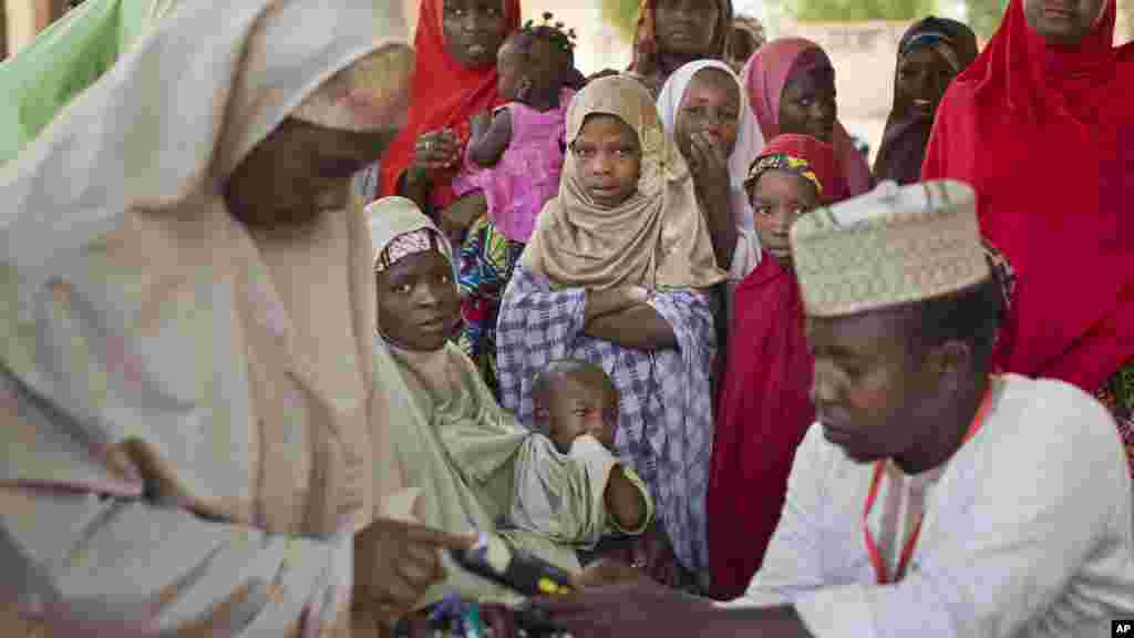 Wasichana wa Nigeria kutoka kabila Hausa kusubiri kama mama zao foleni ili adhibitishe kadi zao za kupiga kura , katika kituo cha kupigia kura ziko katika shule ya Kiislamu katika Daura , kaskazini mwa Nigeria, Machi 28, 2015 .