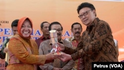 Menteri Dalam Negeri Tjahjo Kumolo (kanan) menyerahkan piala IMP 2014 kepada Walikota Surabaya, Tri Rismaharini, 12 Maret 2015 (Foto: VOA/Petrus)