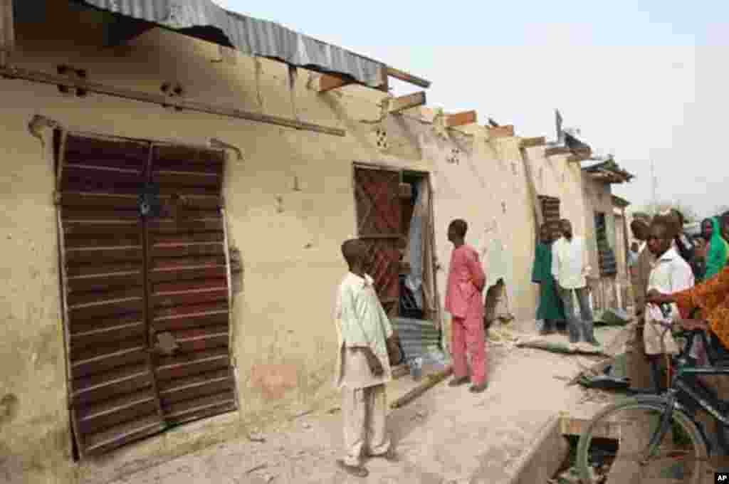 People stand in front of a destroyed building after a blast at Gombomru local market on Monday, in Nigeria's northern city Maiduguri February 7, 2012.