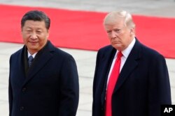 FILE - U.S. President Donald Trump, right, walks with Chinese President Xi Jinping during a welcome ceremony at the Great Hall of the people in Beijing, Nov. 9, 2017.