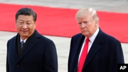 FILE - U.S. President Donald Trump, right, walks with Chinese President Xi Jinping during a welcome ceremony at the Great Hall of the people in Beijing, Nov. 9, 2017. 