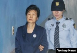 한국의 박근혜(왼쪽) 전 대통령이 13일 서울중앙지법 속행공판에 출석하기 위해 호송차에서 내려 법정으로 향하고 있다.