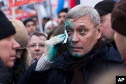 Former Russian Prime Minister Mikhail Kasyanov wipes paint off his face after he was attacked during a march in memory of opposition leader Boris Nemtsov in Moscow, Russia, Feb. 26, 2017.