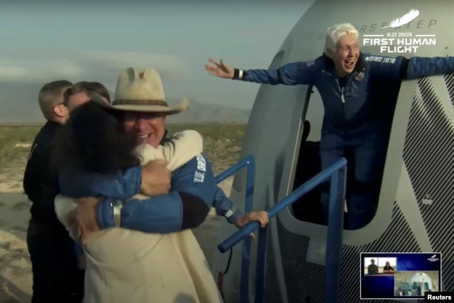 Pengusaha miliarder Jeff Bezos dan penerbang wanita Wally Funk, keluar dari kapsul setelah penerbangan suborbital tanpa pilot pertama di dunia dengan roket New Shepard Blue Origin, mendarat di dekat Van Horn, Texas, AS, 20 Juli 2021. (REUTERS)