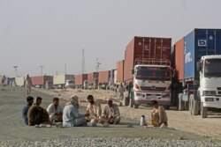 Para pengemudi beristirahat di dekat truk kontainer mereka, menunggu di kota perbatasan Chaman, Pakistan, untuk memasuki Afghanistan, 30 Agustus 2021. ( AFP)