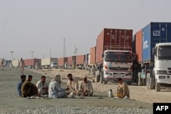 Para pengemudi beristirahat di dekat truk kontainer mereka, menunggu di kota perbatasan Chaman, Pakistan, untuk memasuki Afghanistan, 30 Agustus 2021. ( AFP)