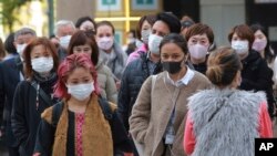 People wearing face masks to protect against the spread of the coronavirus walk along a street in Tokyo, Nov. 29, 2021.