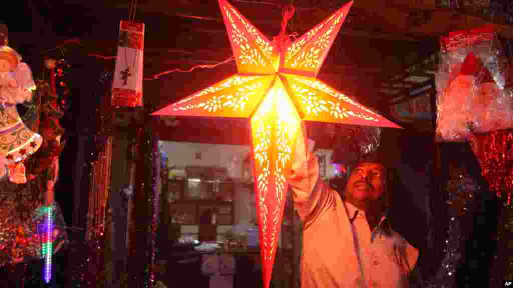 Un vendeur indien tient une étoile décorative qu&#39;il propose&nbsp;à un client avant Noël à Ahmadabad, en Inde, mardi 23 décembre 2014