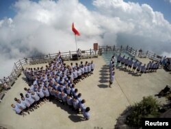 FILE - Veterans of the Chinese People's Liberation Army (PLA) Navy stand in formation of a star and the Chinese characters "August 1" on top of a mountain ahead of China's "Army Day" in Luoyang, Henan province, July 31, 2016.