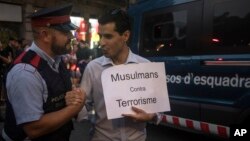 A Catalan policeman shakes hands with a demonstrator holding a banner that reads: "Muslims Against Terrorism," during a protest by the Muslim community condemning the attack in Barcelona, Spain, Aug. 21, 2017.