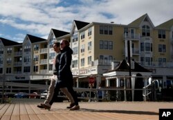 People stroll along the boardwalk at the Pier Village development in Long Branch, New Jersey, March 5, 2018.