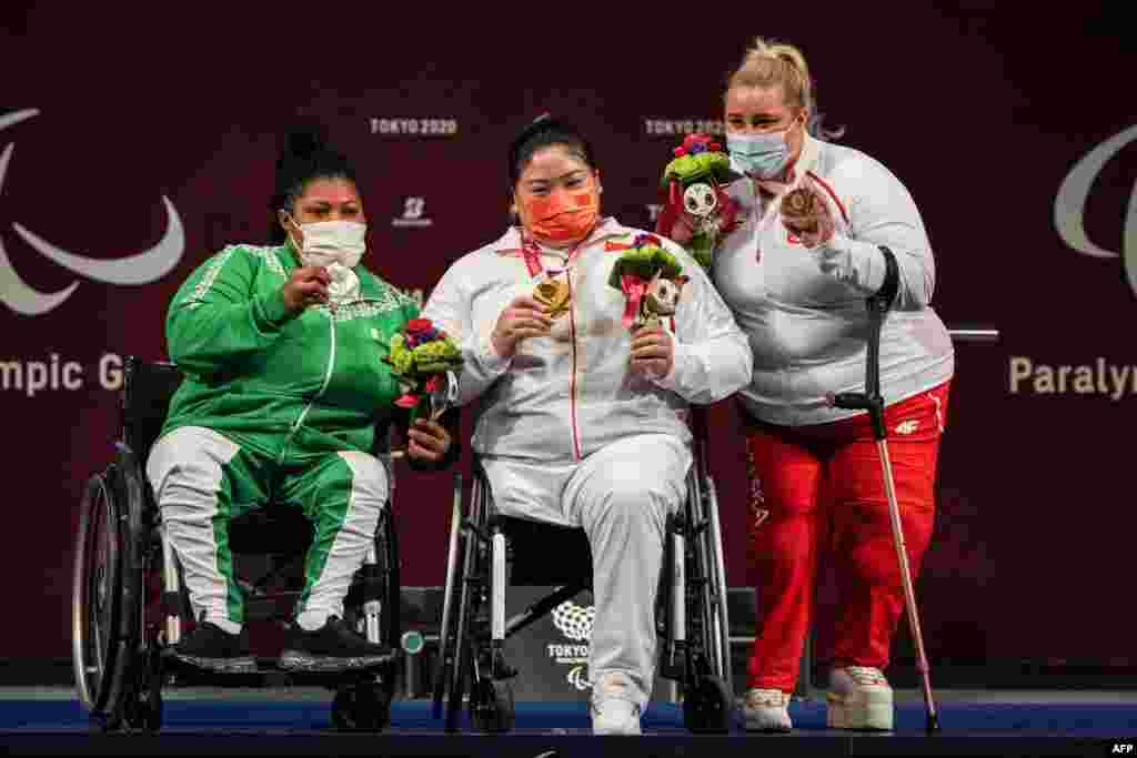 China&#39;s Xuemei Deng (C, gold), Nigeria&#39;s Loveline Obiji (L, silver) and Poland&#39;s Marzena Zieba (bronze) pose for photographers during the victory ceremony of powerlifting women&#39;s +86kg of the Tokyo 2020 Paralympic Games at Tokyo International Forum in Tokyo, Japan. (Photo by Yasuyoshi CHIBA / AFP)