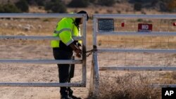 A security guard at the entrance to the Bonanza Creek Ranch film set locks the gate after turning away workers who came to pick up equipment in Santa Fe, N.M., Oct. 25, 2021.