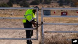 Seorang petugas keamanan di pintu masuk syuting film Bonanza Creek Ranch mengunci gerbang setelah mengusir pekerja yang datang untuk mengambil peralatan di Santa Fe, 25 Oktober 2021. (Foto: AP)