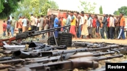 Suspected fighters are paraded before the media by Burundian police near a recovered cache of weapons after clashes in the capital, Bujumbura, Dec. 12, 2015. 