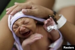 Sueli Maria (obscured) holds her daughter Milena, who has microcephaly, (born seven days ago), at a hospital in Recife, Brazil, Jan. 28, 2016.